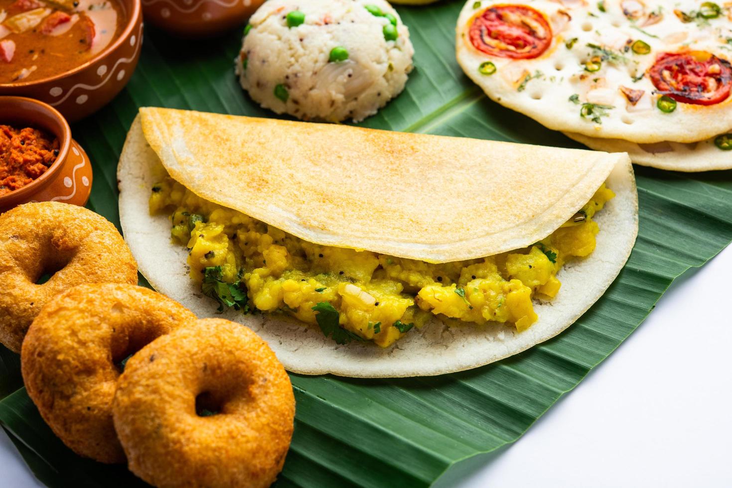 South Indian Masala Dosa, Uttapam, Idli vada sambar, semolina halwa, upma served over banana leaf photo