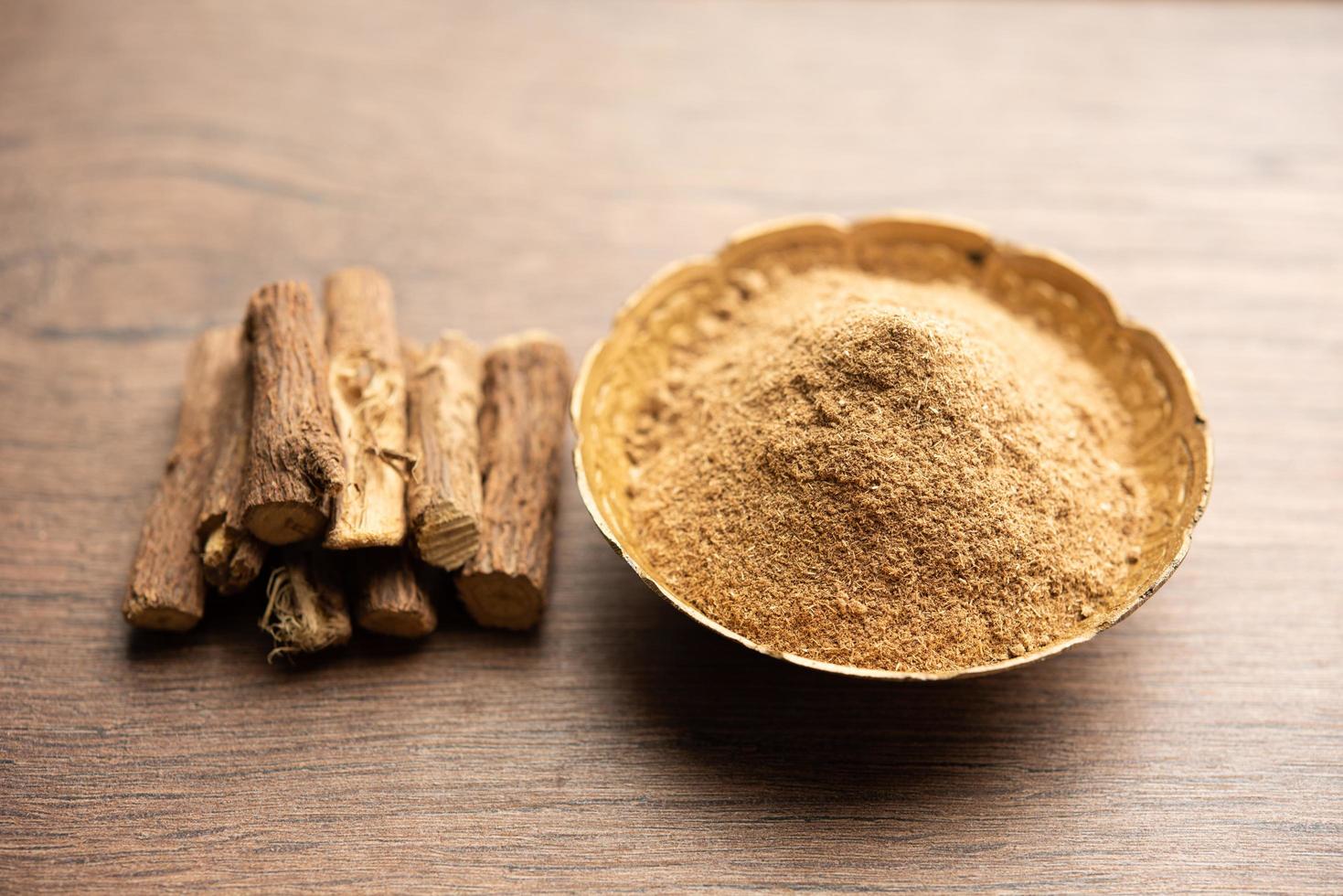 Ayurvedic Mulethi or Liquorice root stick or jeshthamadh powder served in a bowl over moody background photo