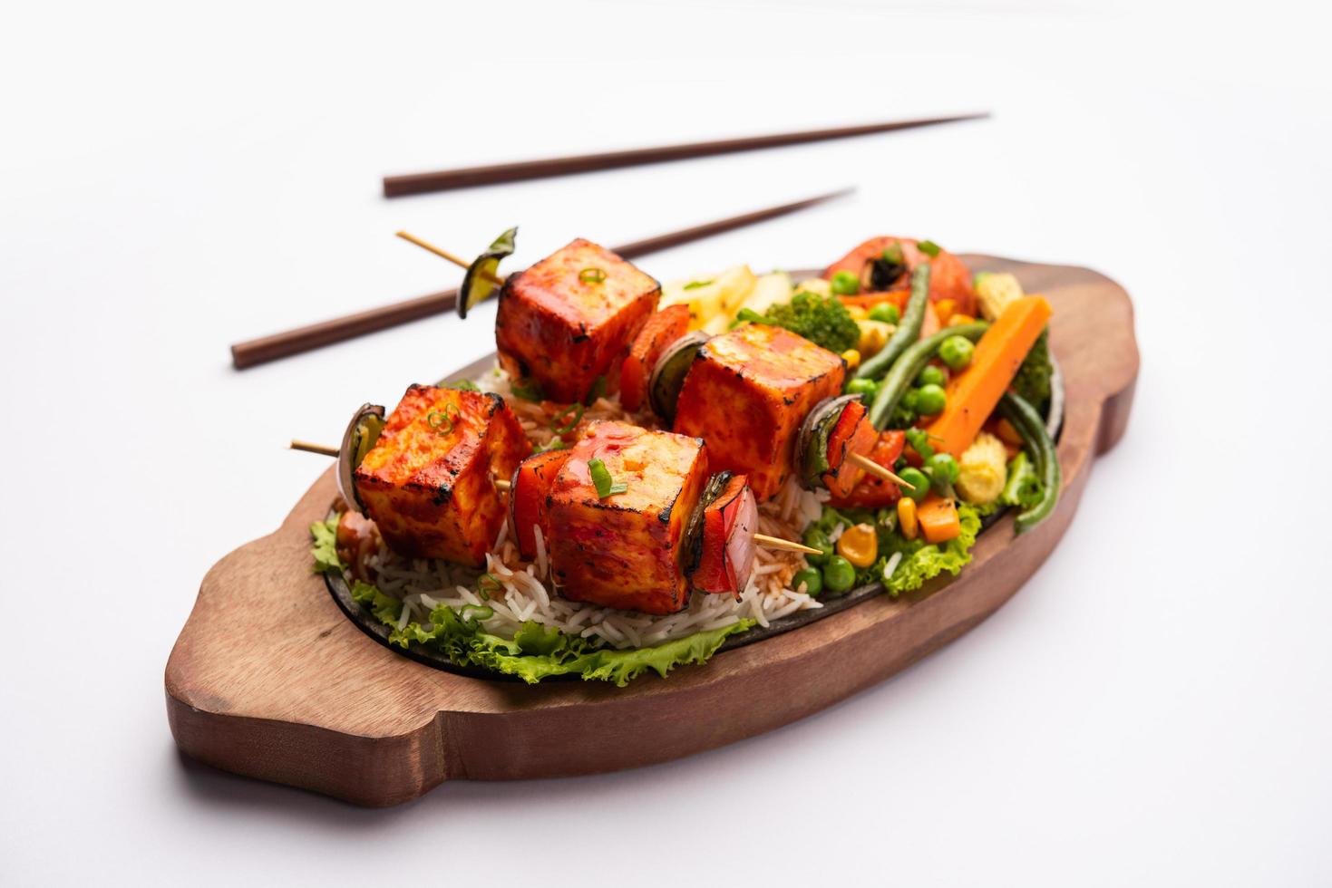 paneer sizzler es una versión india con requesón, ensalada servida chisporroteando en un plato de piedra caliente. foto