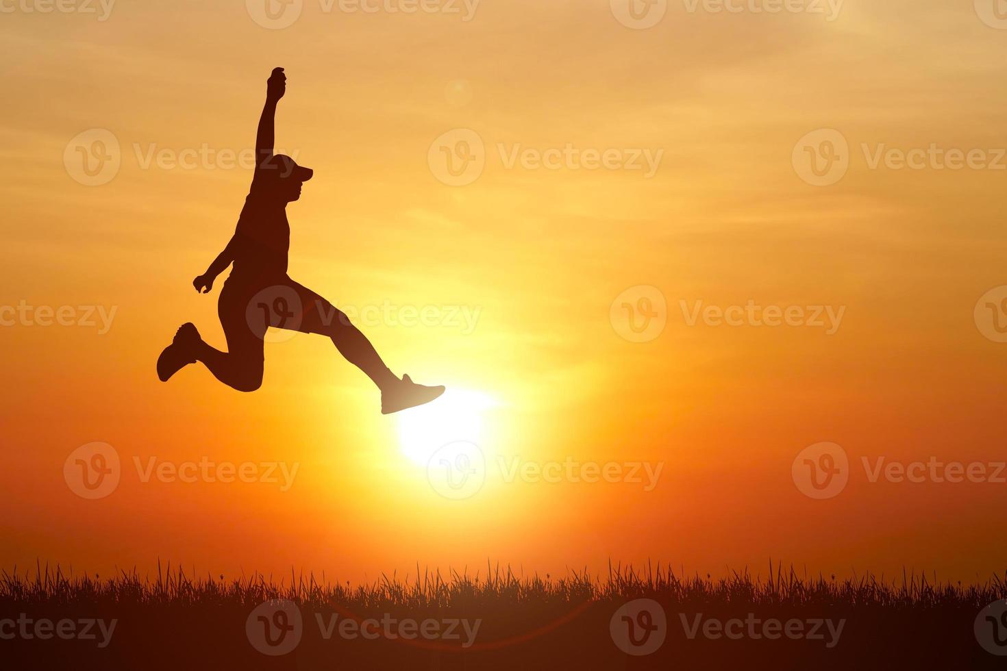 Silhouette. Man jumping happily in the meadow. photo
