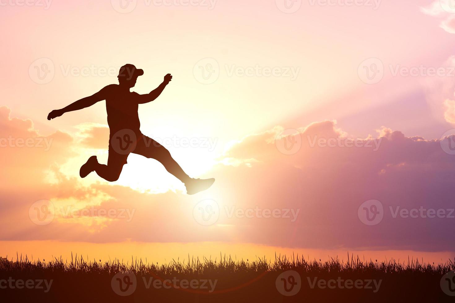 Silhouette. Man jumping happily in the meadow. photo