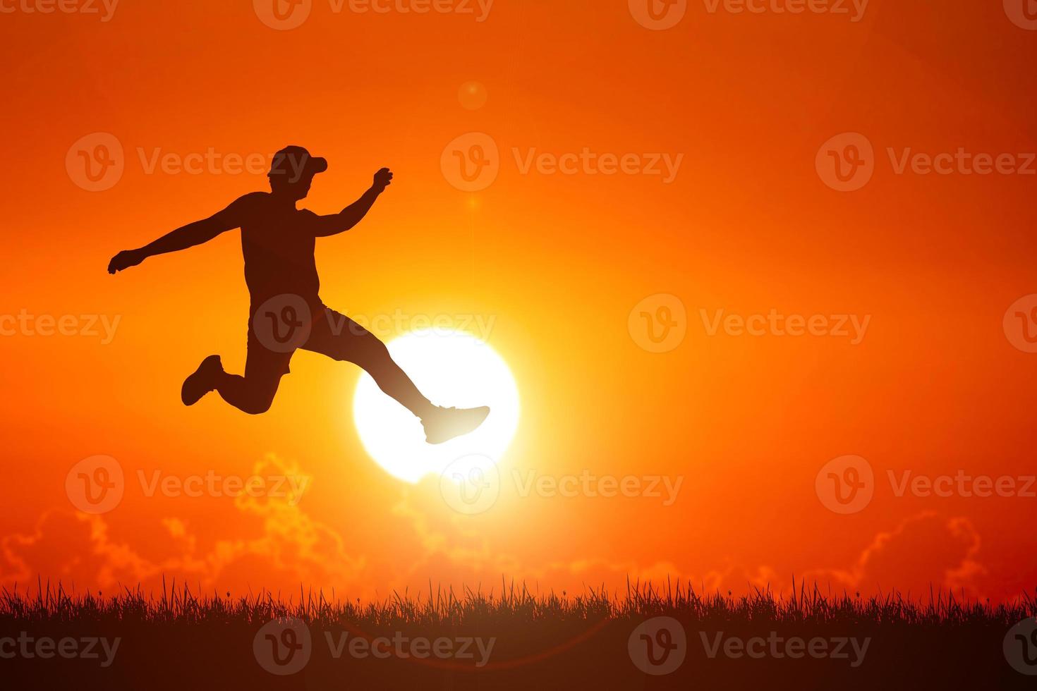 Silhouette. Man jumping happily in the meadow. photo
