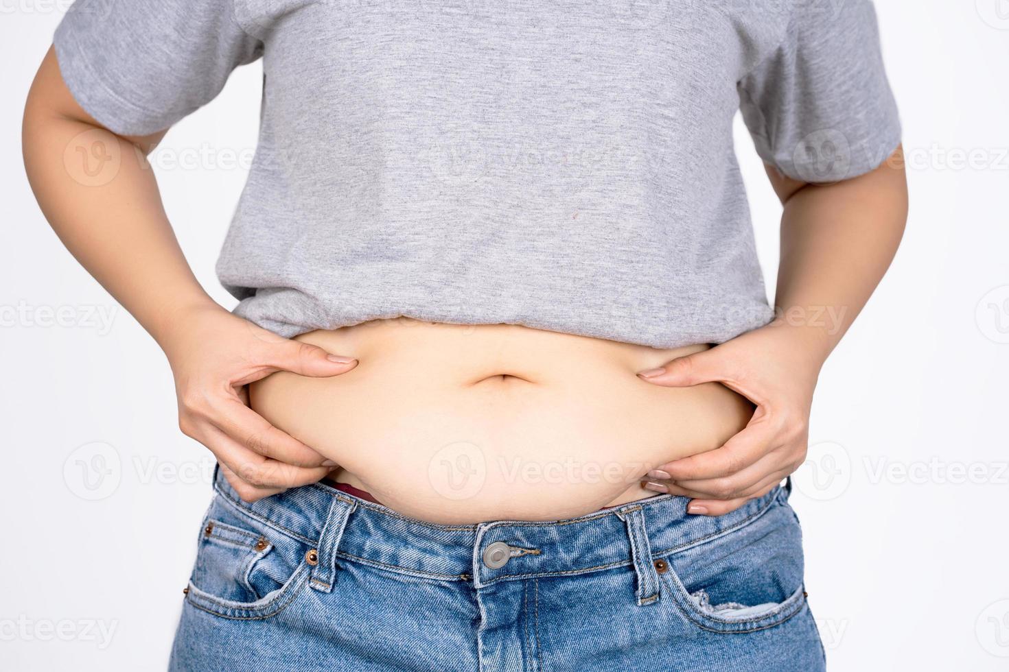 Woman's hand holding belly on white background with copy space. Obesity concept. photo