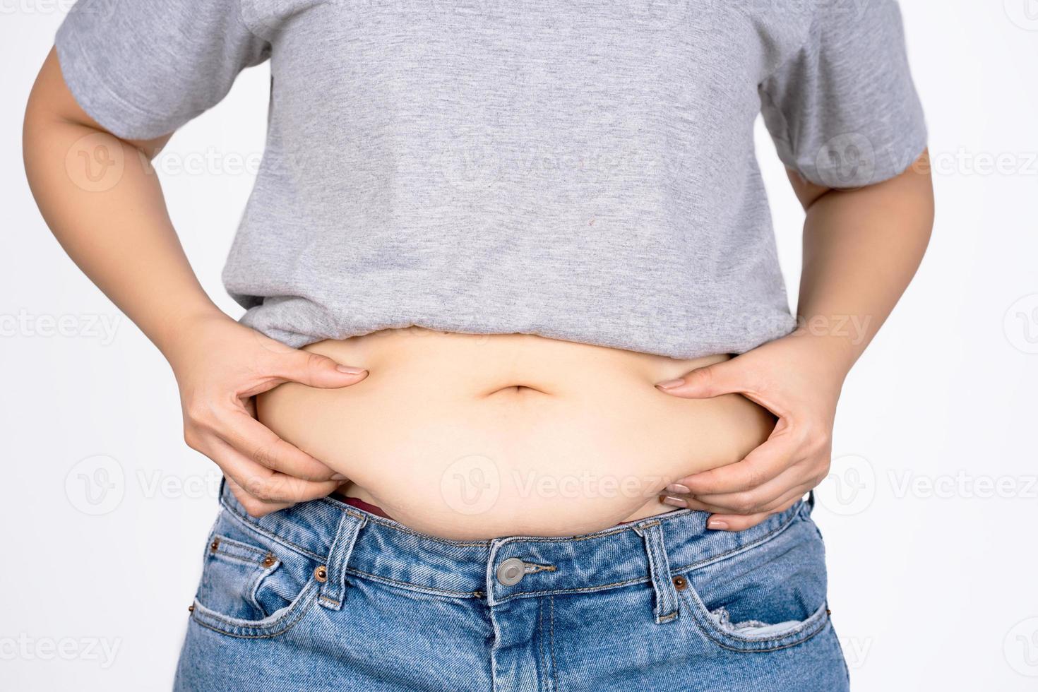 mano de mujer sosteniendo el vientre sobre fondo blanco con espacio de copia. concepto de obesidad. foto