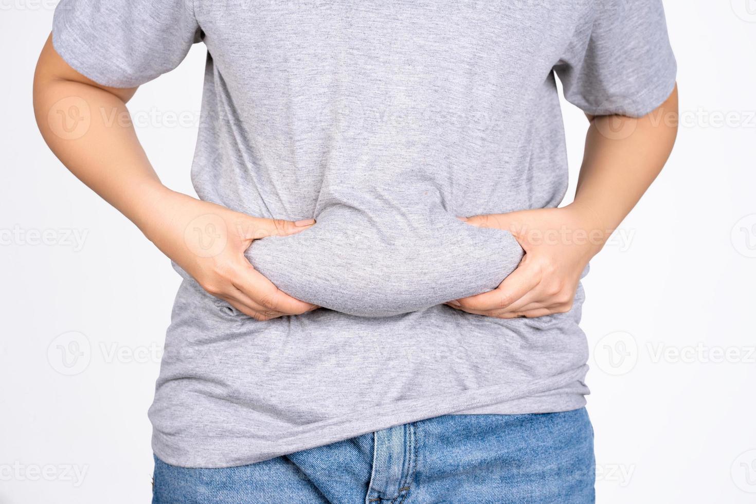 Asian fat women has overweight in jeans. woman's hand holding excessive belly fat isolated on white background. concept of surgery and subcutaneous fat breakdown. photo