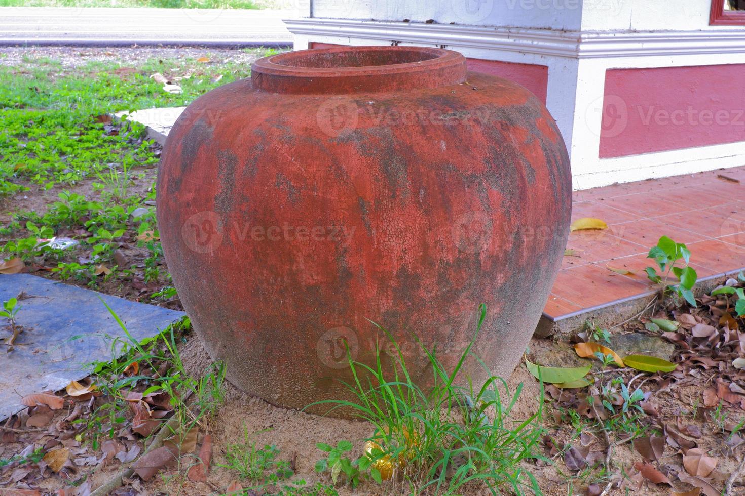 old clay jar was left on the ground beside the road photo