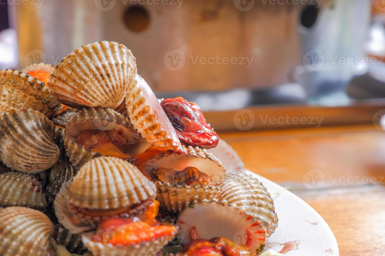 Steamed cockles boiled cockles are placed on a white plate. Garnished with sliced tomatoes. photo