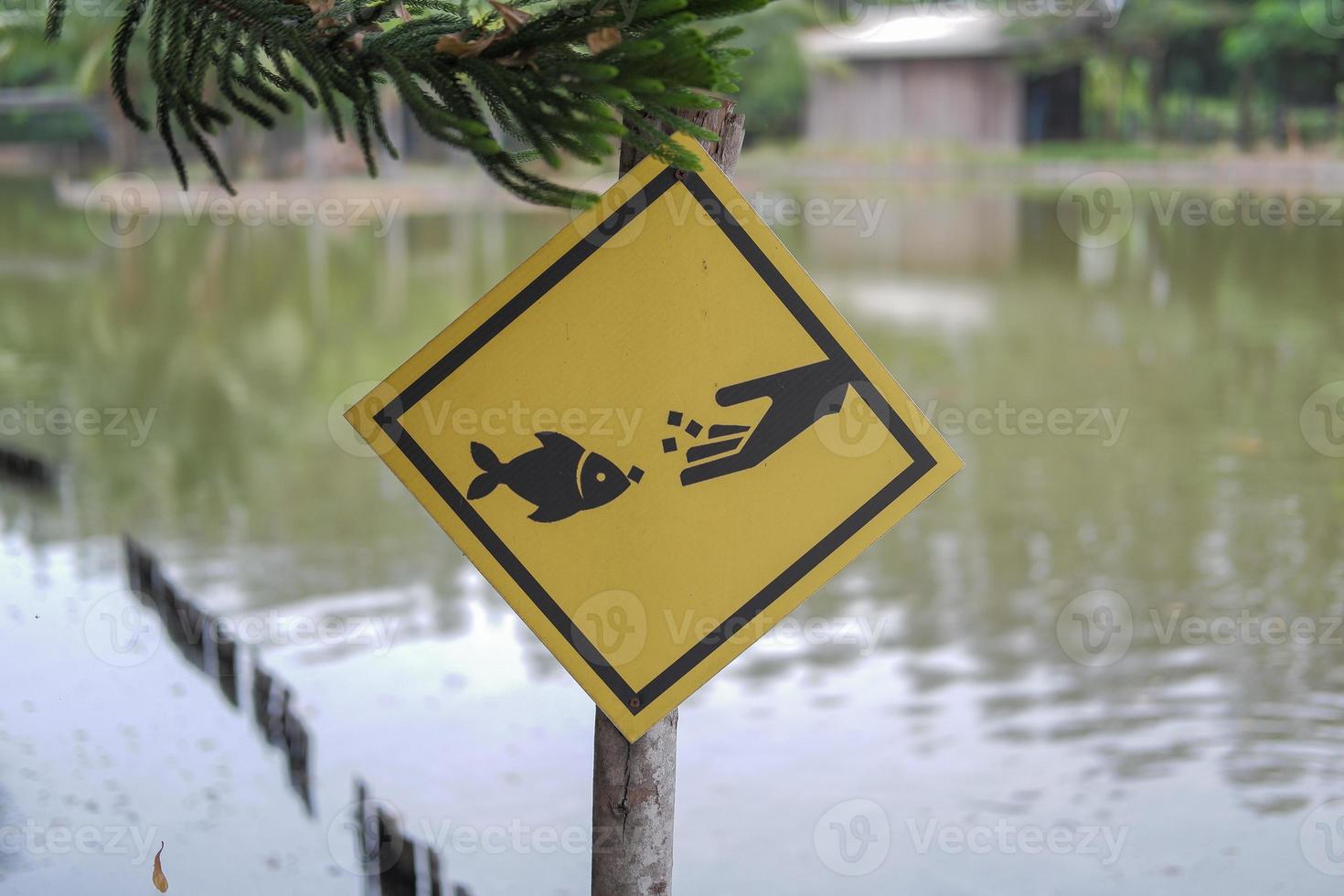 A pillar with a yellow sign indicates this area is for fish feeding. photo