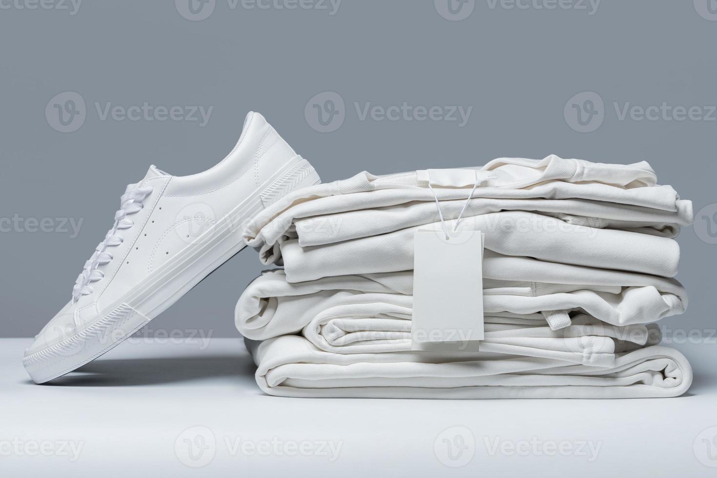 Stack of new white clothes with a blank garment tag photo