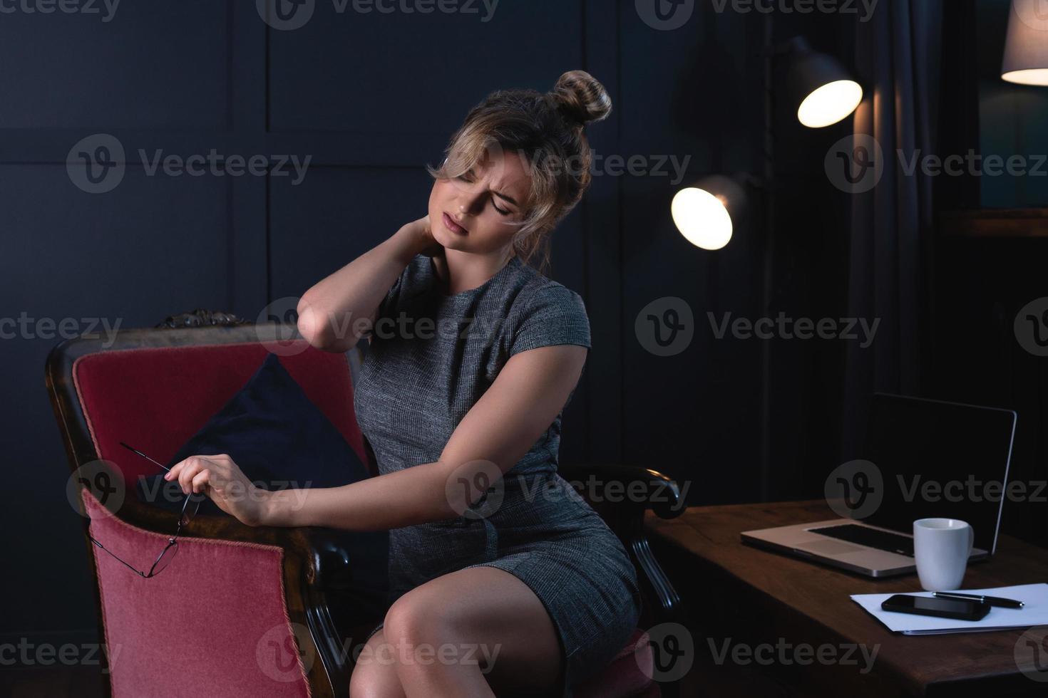 Tired businesswoman with a neck pain during late night work in office. photo