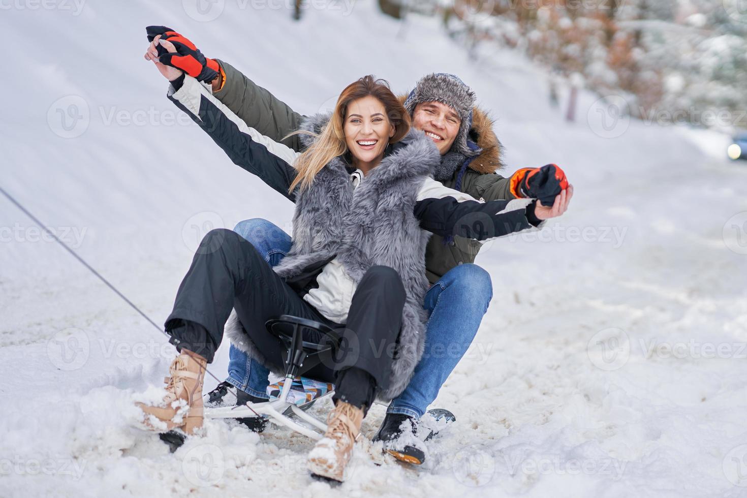 Couple having fun with sledge on snow in winter photo