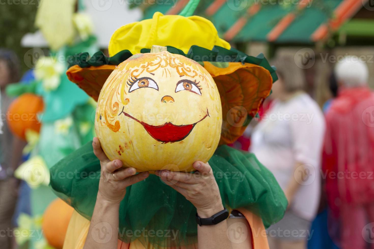 Creatively decorated Halloween pumpkins in human hands. A kind face with a smile painted on a pumpkin. Carnival costume for the autumn holiday. photo