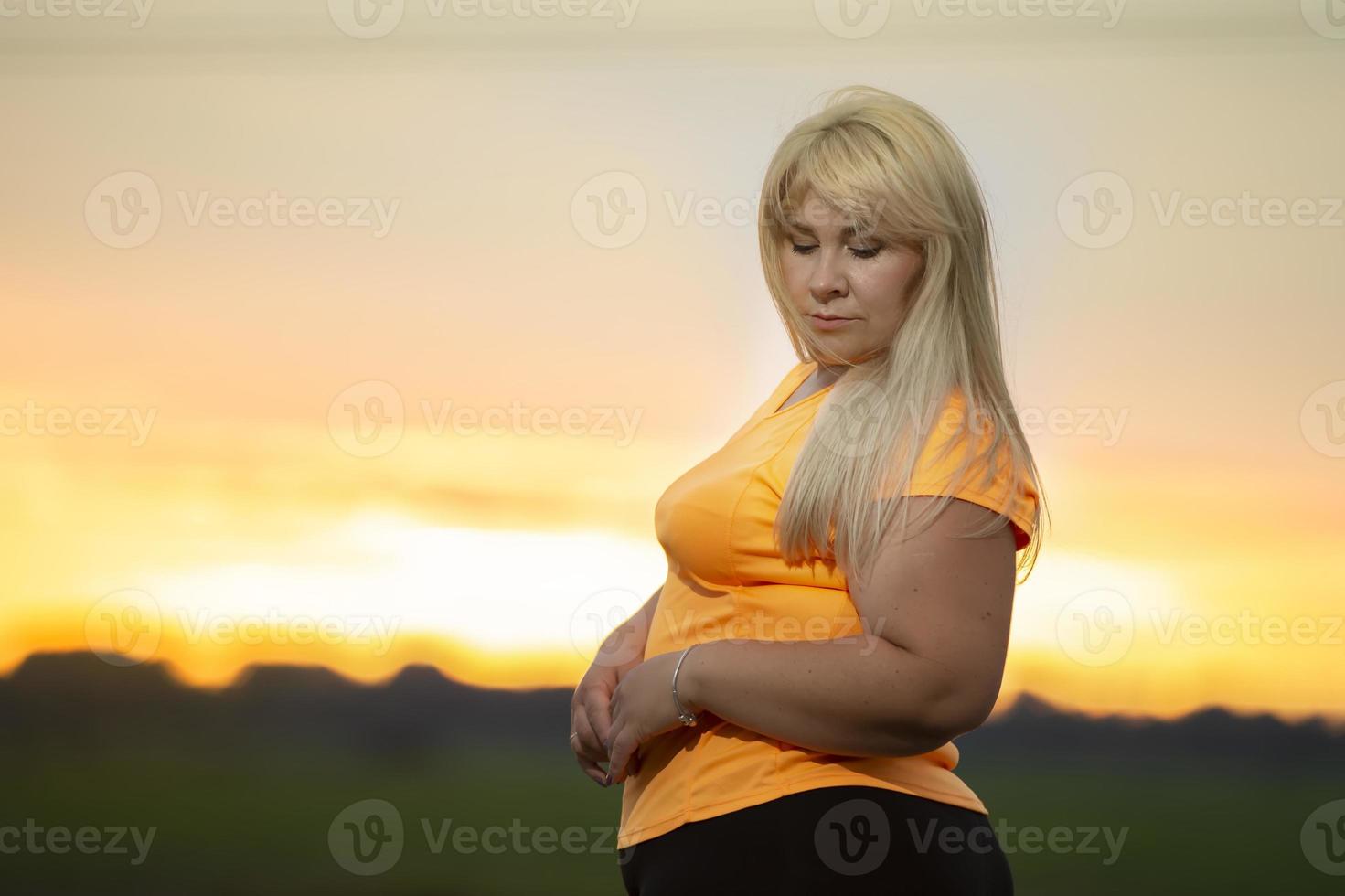 Portrait of a European middle-aged woman in a tracksuit, posing for the camera, relaxing. excited overweight woman in trendy tracksuit resting after exercising. photo