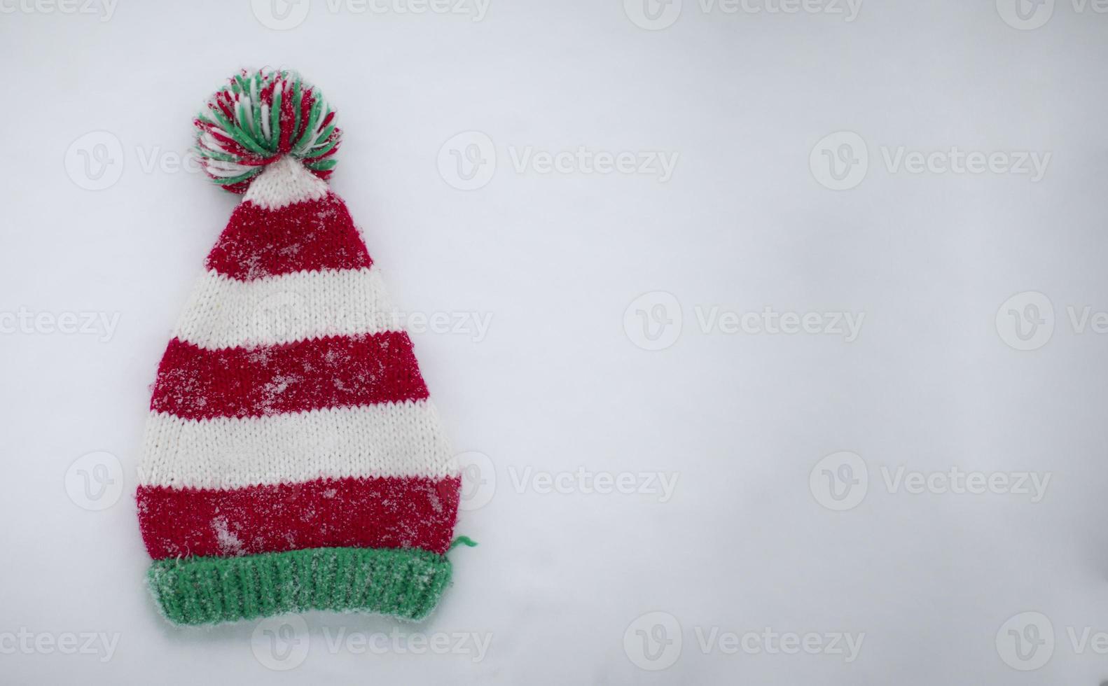 Knitted Christmas hat on a white background. Funny Christmas hat on snow background. photo