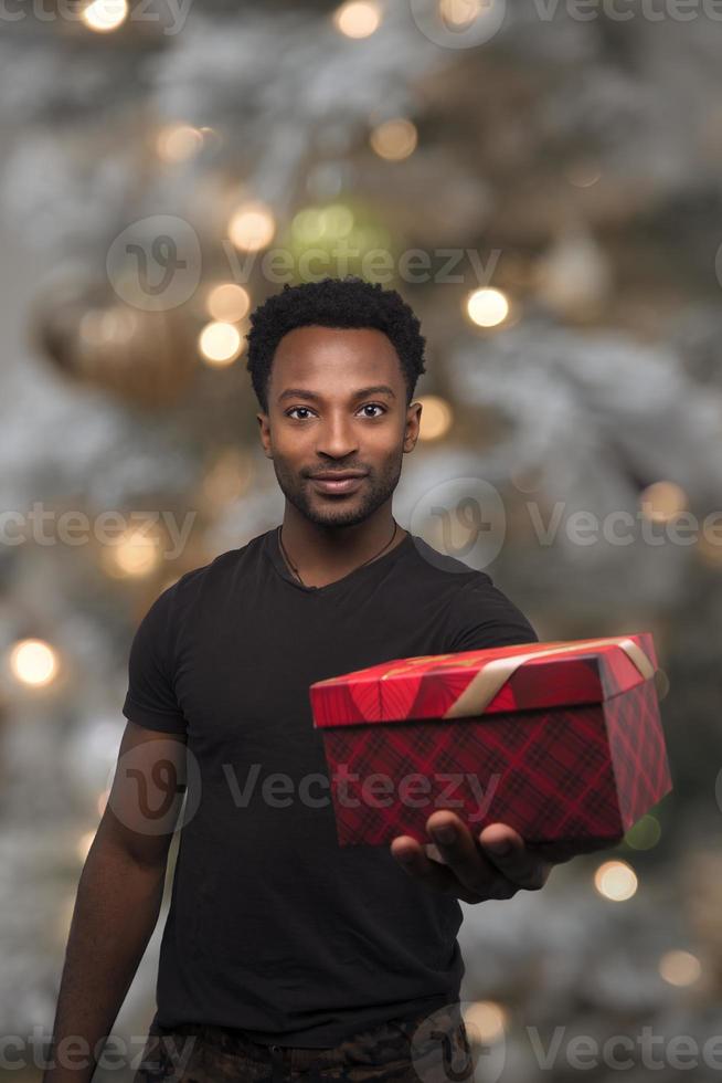 christmas present man showing surprise giving gift box holiday celebration on illuminated bokeh fir tree photo