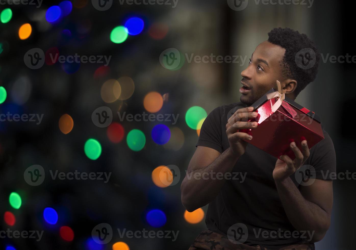 man shaking his christmas gift to listen to the noise and guess what it is bokeh lights photo