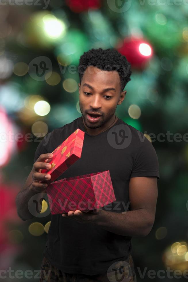 man opening box looking inside christmas gift surprise excited expression with bokeh light photo