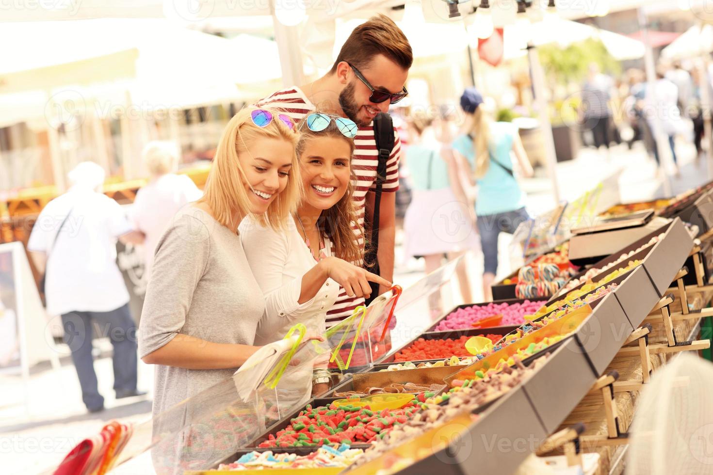 Group of friends buying jelly sweets on market photo