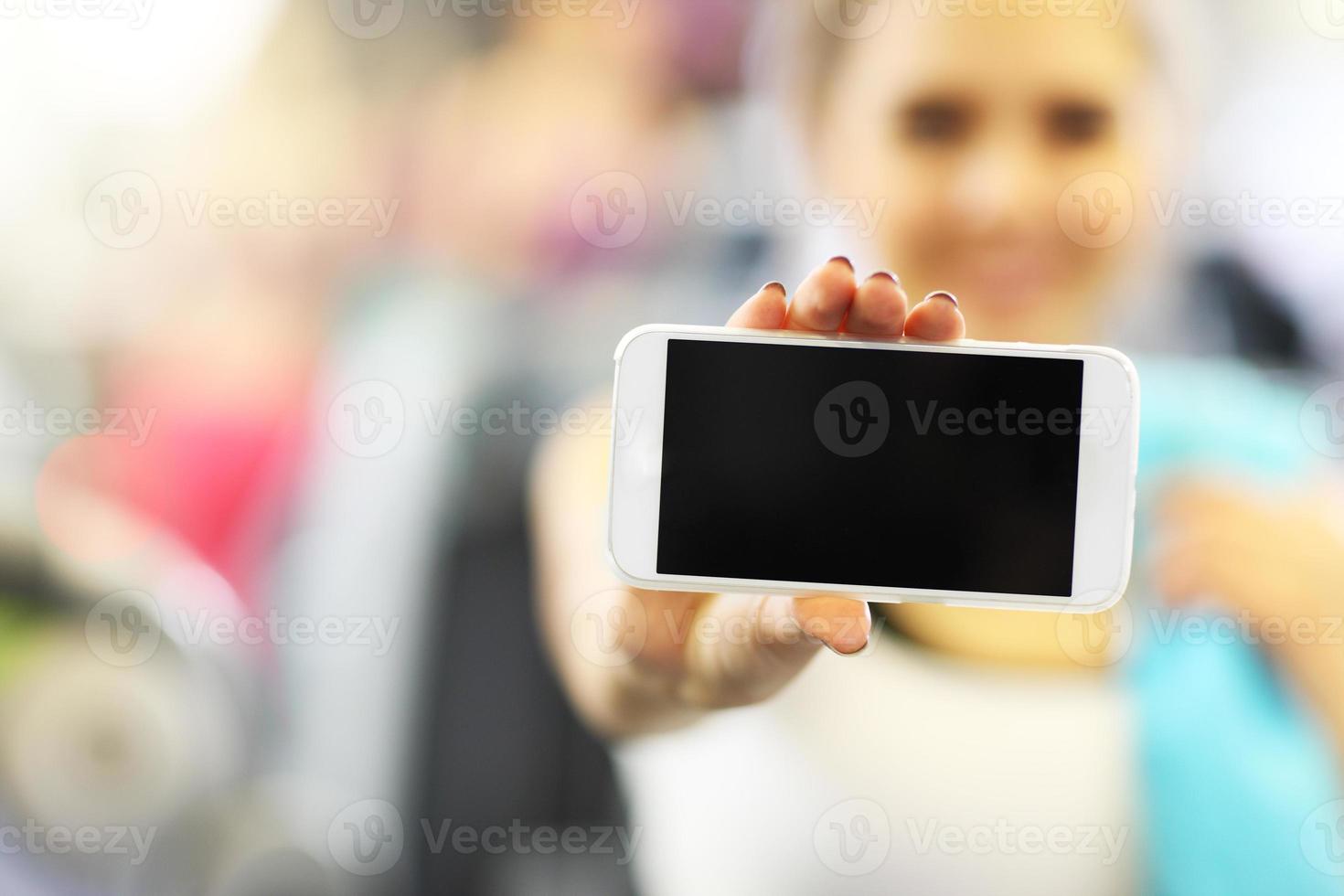 Woman holding smartphone in gym photo