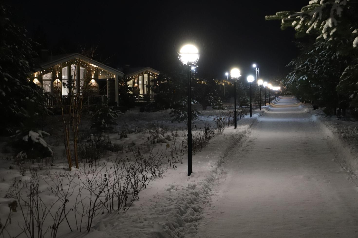 Christmas mood. Country street and cottages illuminated and decorated in the darkness surrounded by snowdrifts. i photo