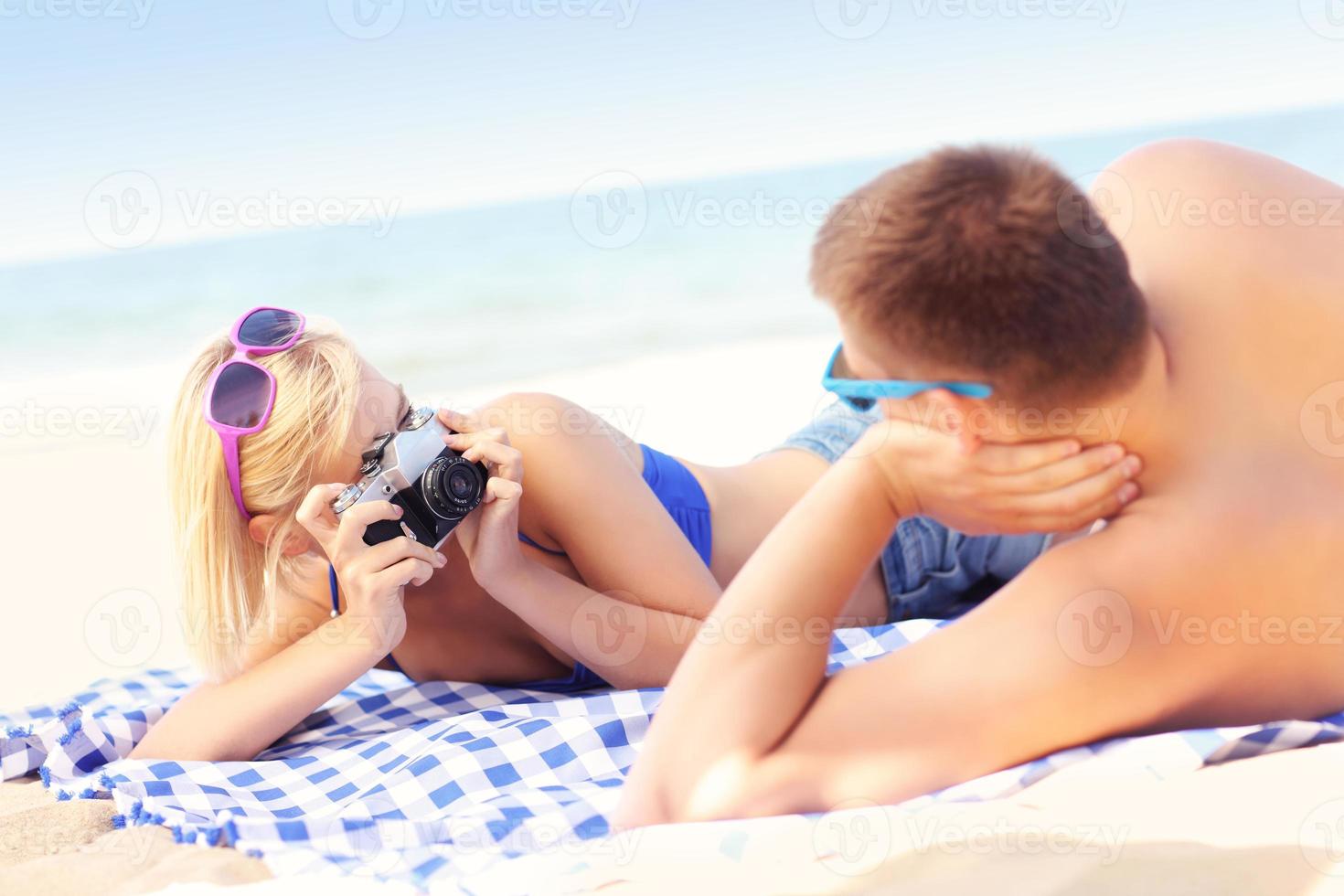Woman taking a picture of her boyfriend at the beach photo