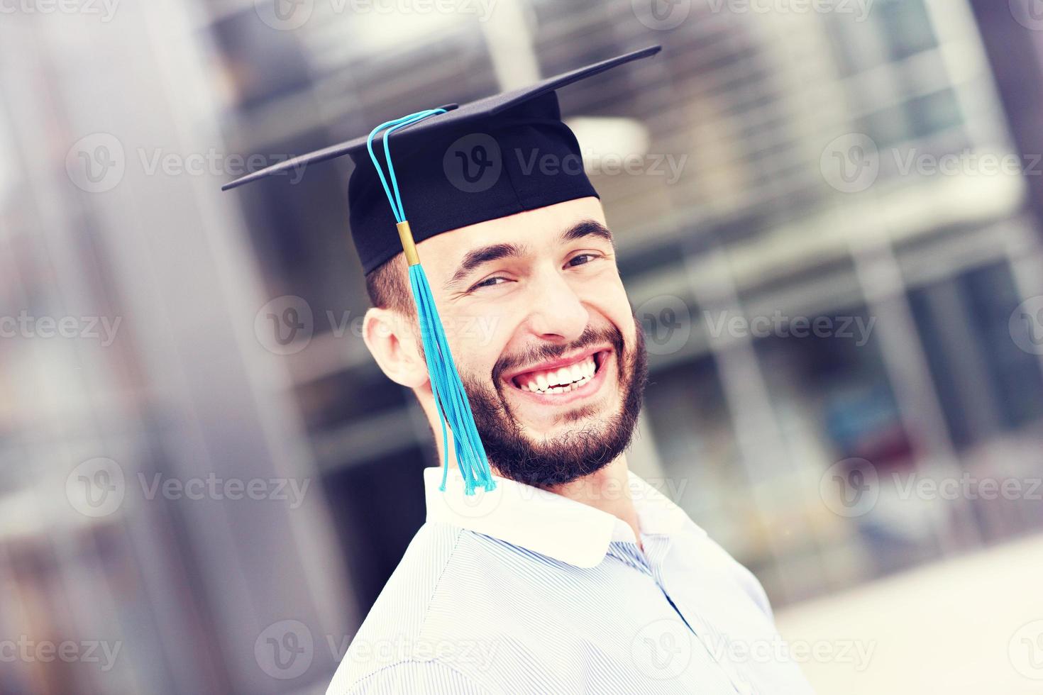 Cheerful graduate outside modern building photo