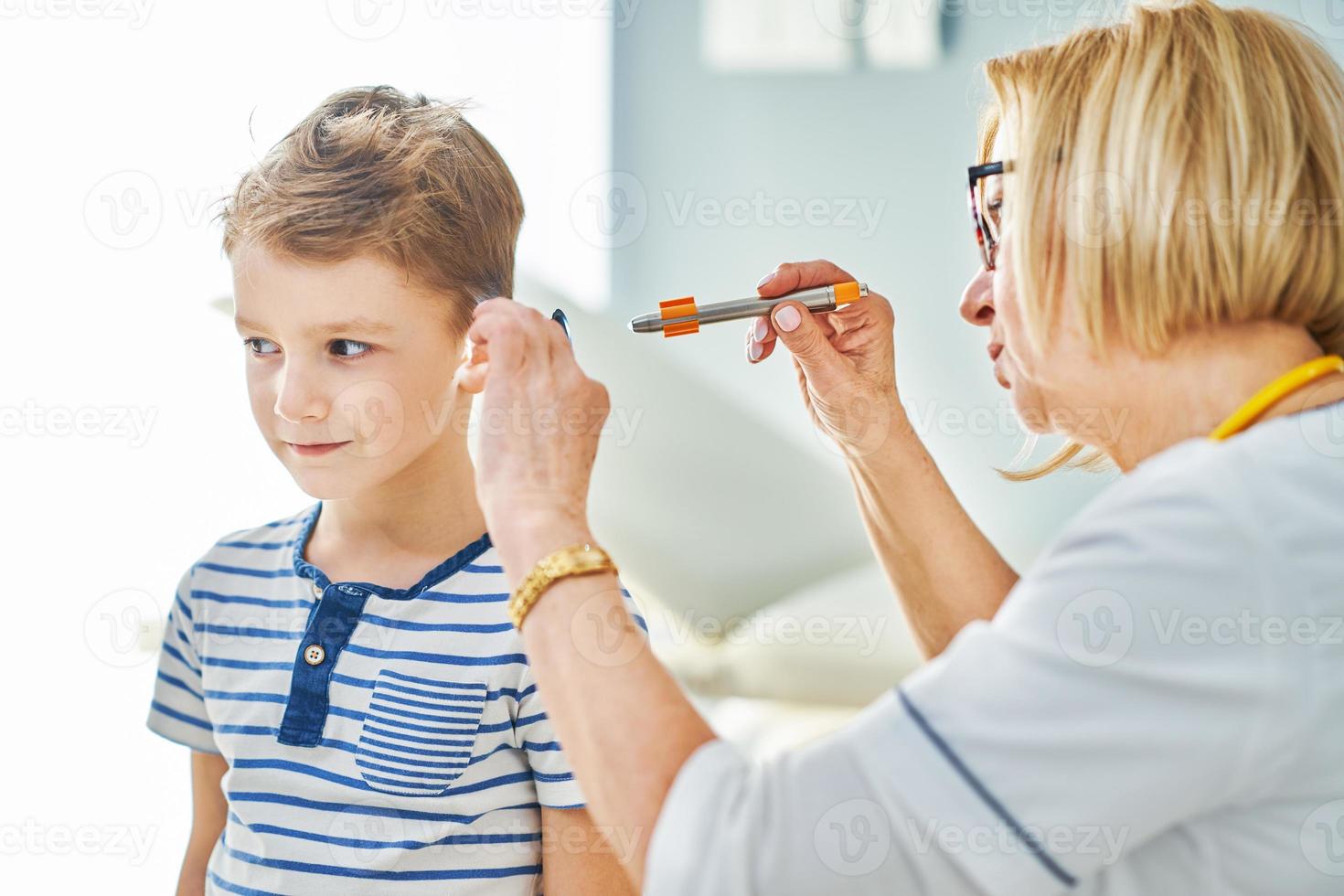 Pediatrician doctor examining little kids in clinic ears check photo