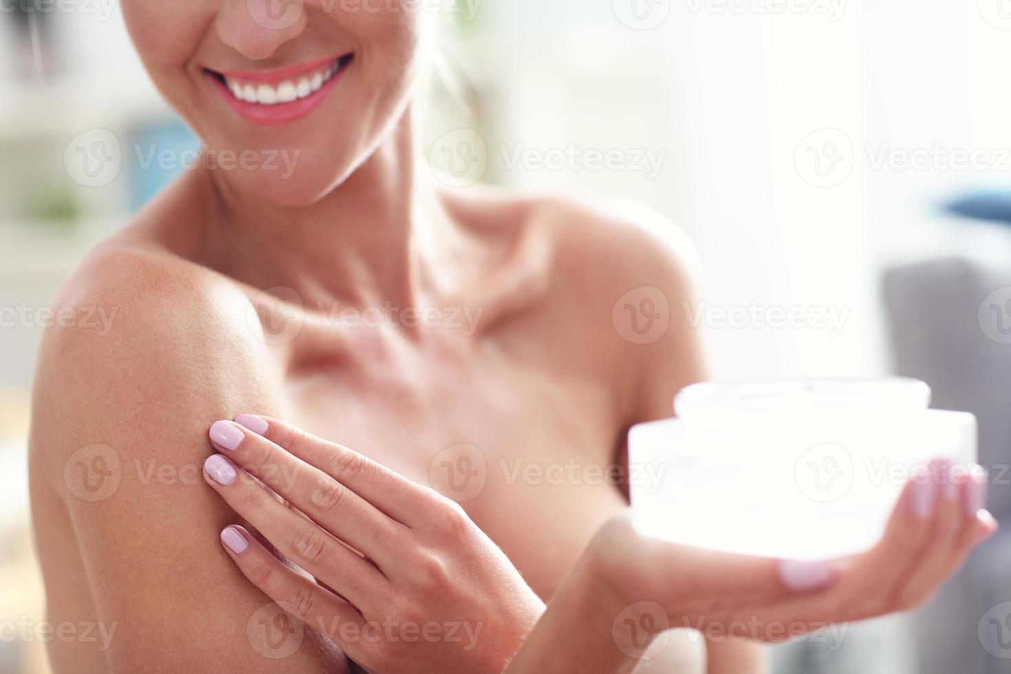 Picture of a fit woman holding lotion over her body photo