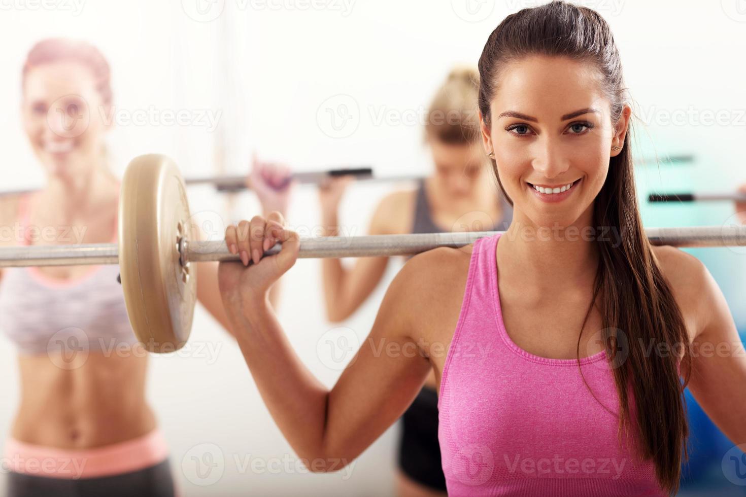 Group of smiling people lifting barbells photo