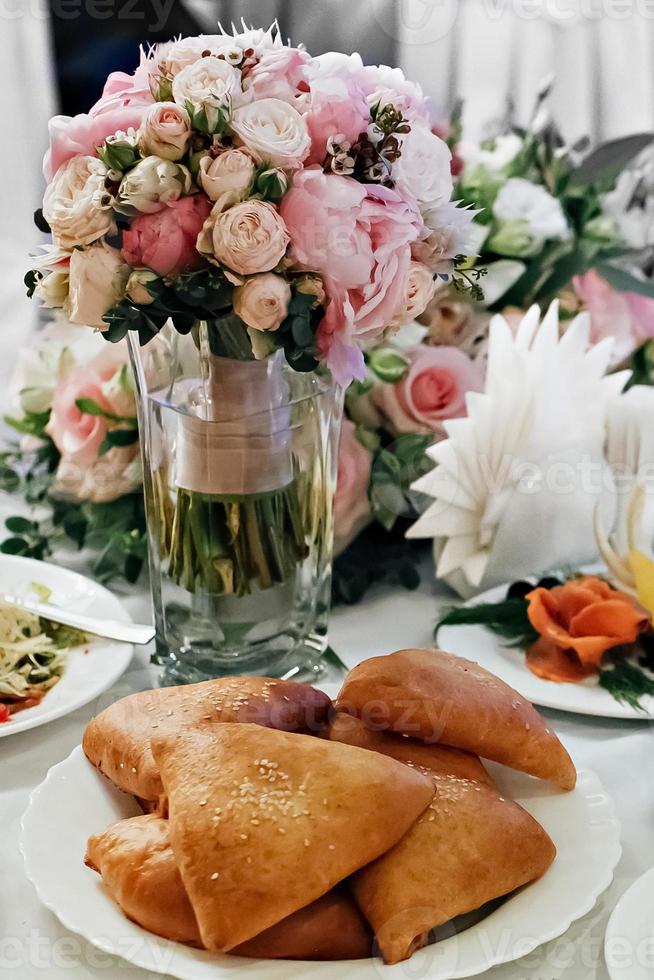 mesa festiva con un ramo de rosas en un jarrón y un plato de tartas foto