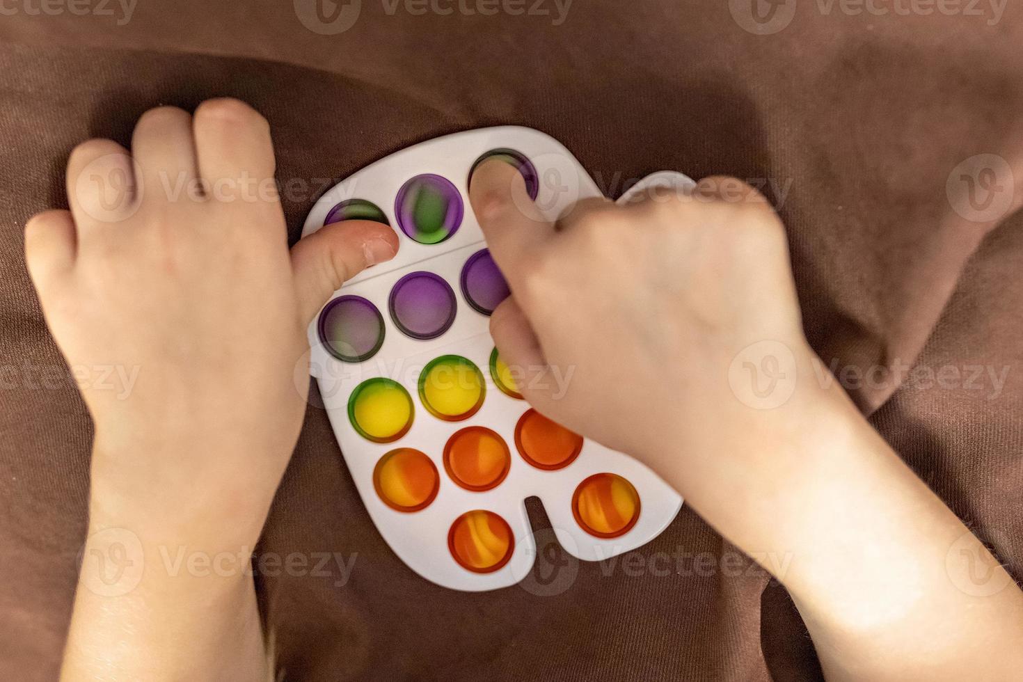 Pop it is a multi-colored anti-stress toy in children's hands. Bubble game. Antistress toys. photo