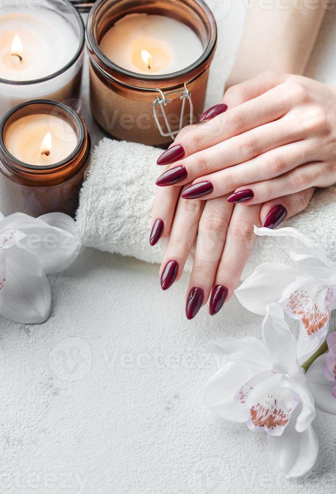 Hands of a young woman with dark red manicure on nails photo