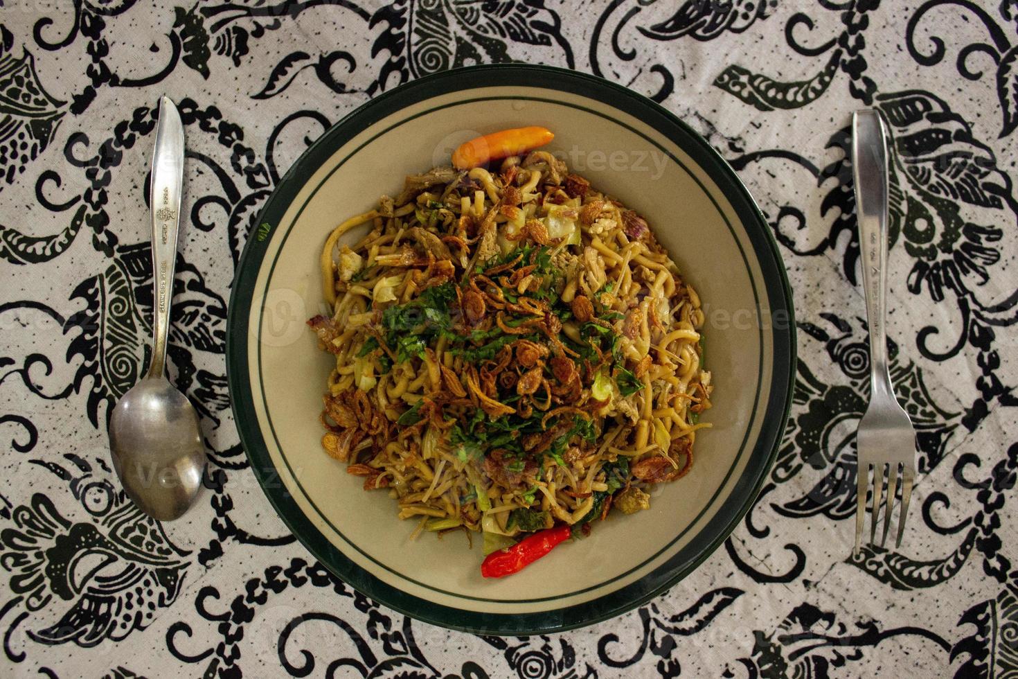 Mie Goreng Jawa or bakmi jawa or java noodle with spoon and fork. Indonesian traditional street food noodles from central java or Yogyakarta, indonesia on white background photo