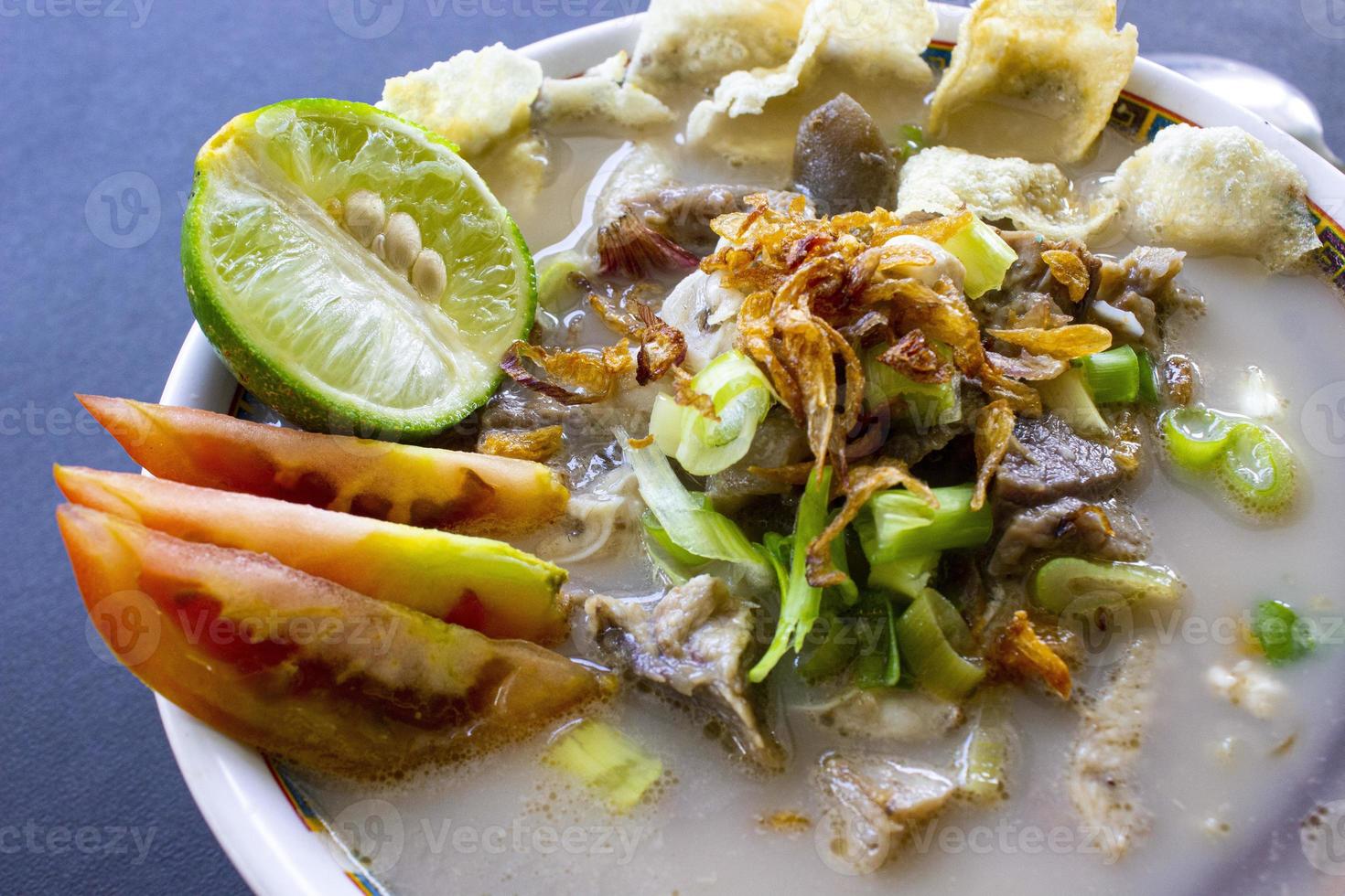 sop kaki kambing a traditional food from Betawi, Jakarta Indonesia, made from mutton or lamb, offal, spices. isolated on black background.This food is like lamb stew on black background photo