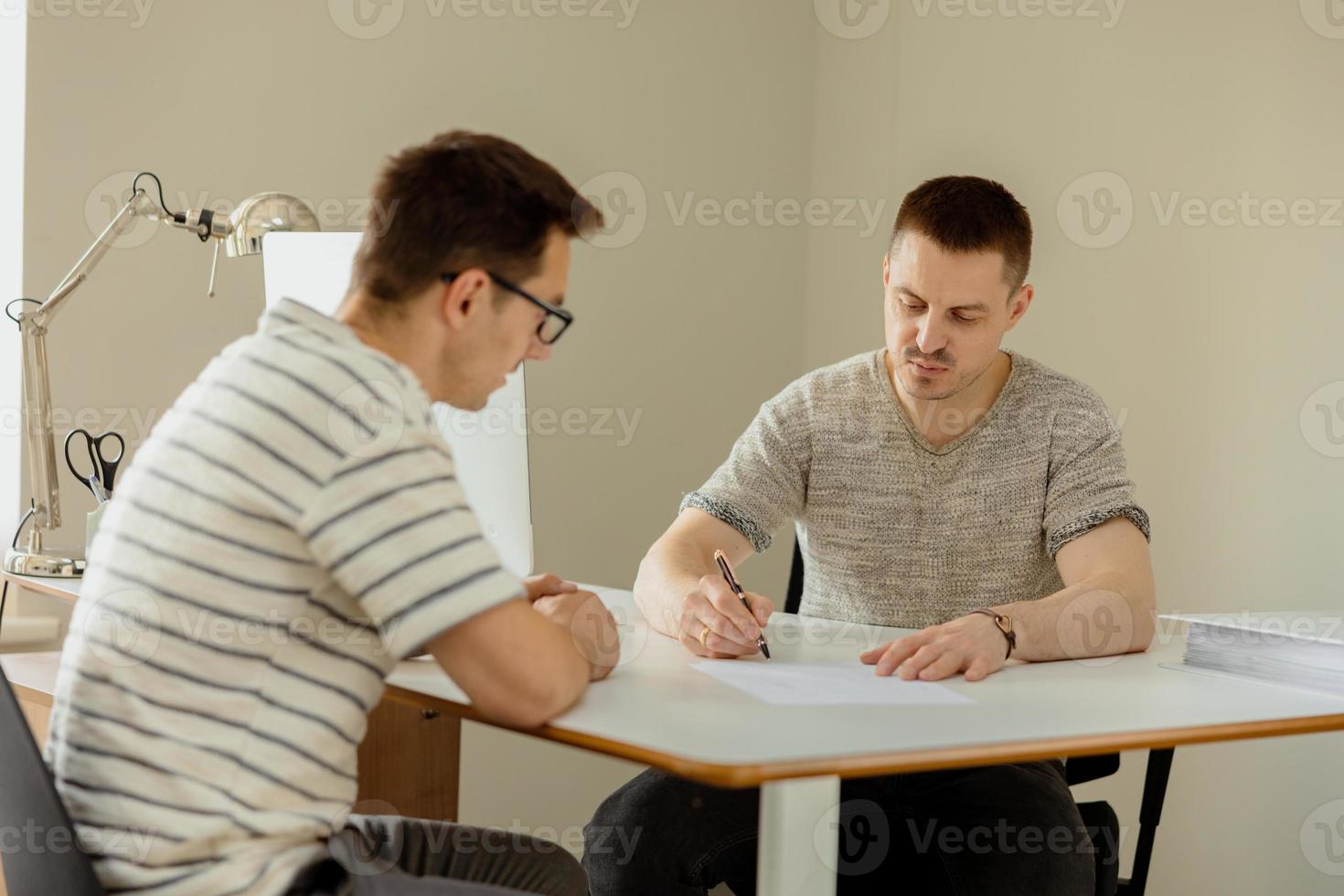 Serious professional man consulting client in office. Two mens having meeting, making business conversation. Insurer giving advice, manager making offer. Mentor teaching intern. Job interview. photo