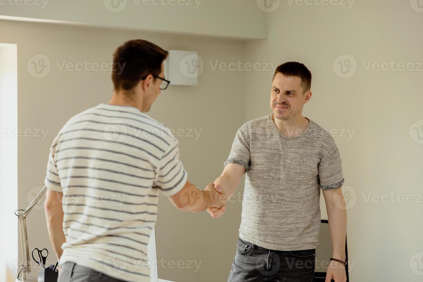 Successful deal. Two businessmen handshaking process. Welcome to our team. Young, serious manager in office shaking hands with a job applicant after an interview. Business partnership handshake. photo