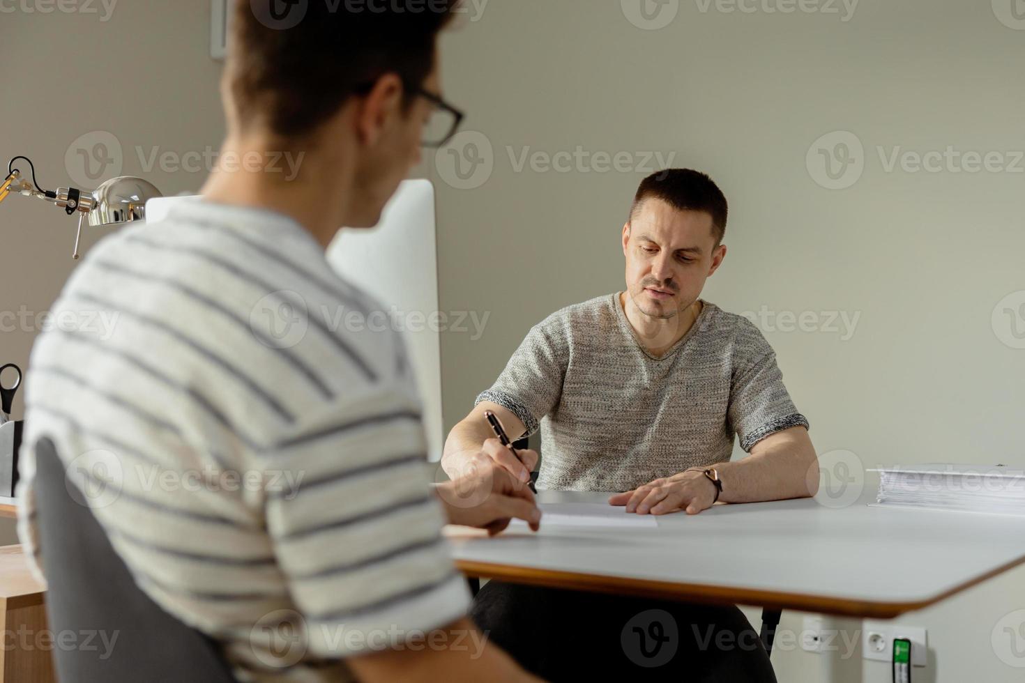 Serious professional man consulting client in office. Two mens having meeting, making business conversation. Insurer giving advice, manager making offer. Mentor teaching intern. Job interview. photo