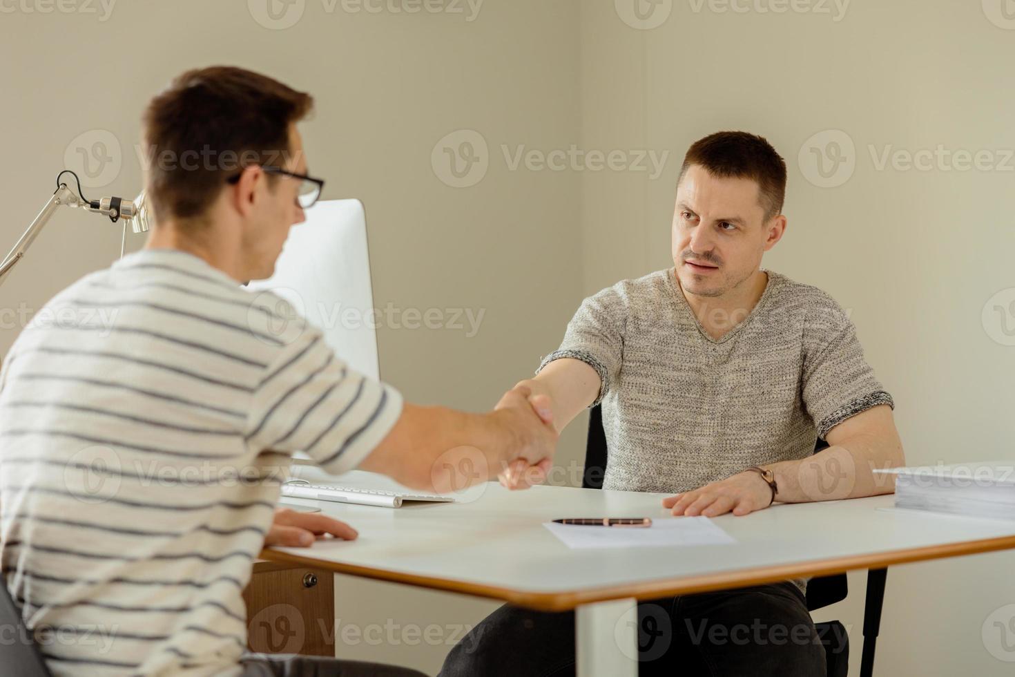 Successful deal. Two businessmen handshaking process. Welcome to our team. Young, serious manager in office shaking hands with a job applicant after an interview. Business partnership handshake. photo