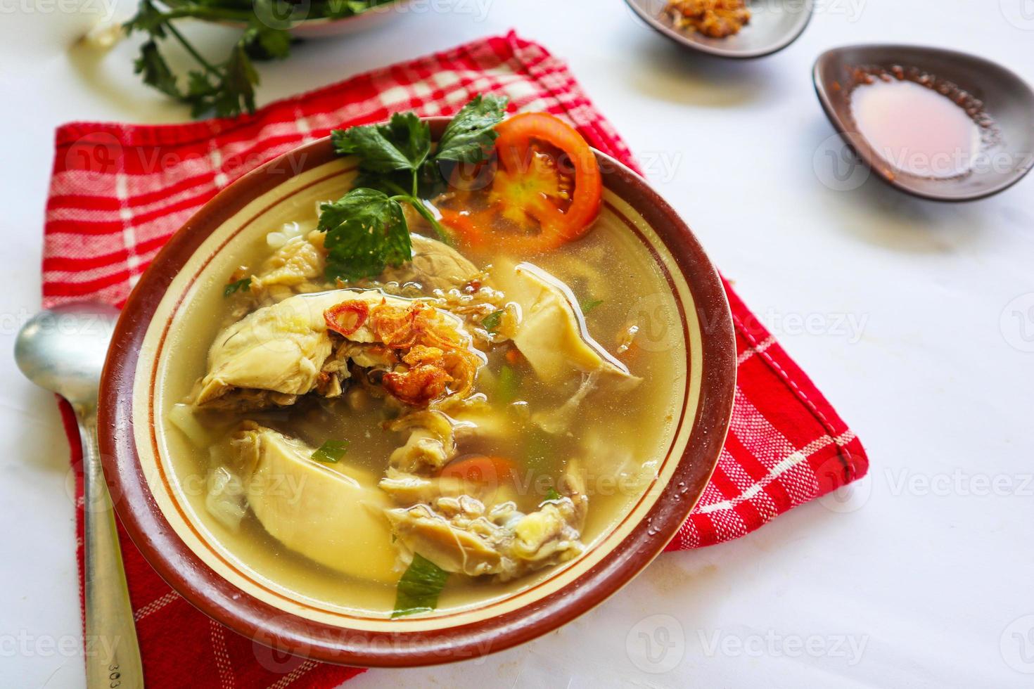 Chicken soup served with vegetables, tomatoes, celery in a bowl, spoon and fork. with black background photo