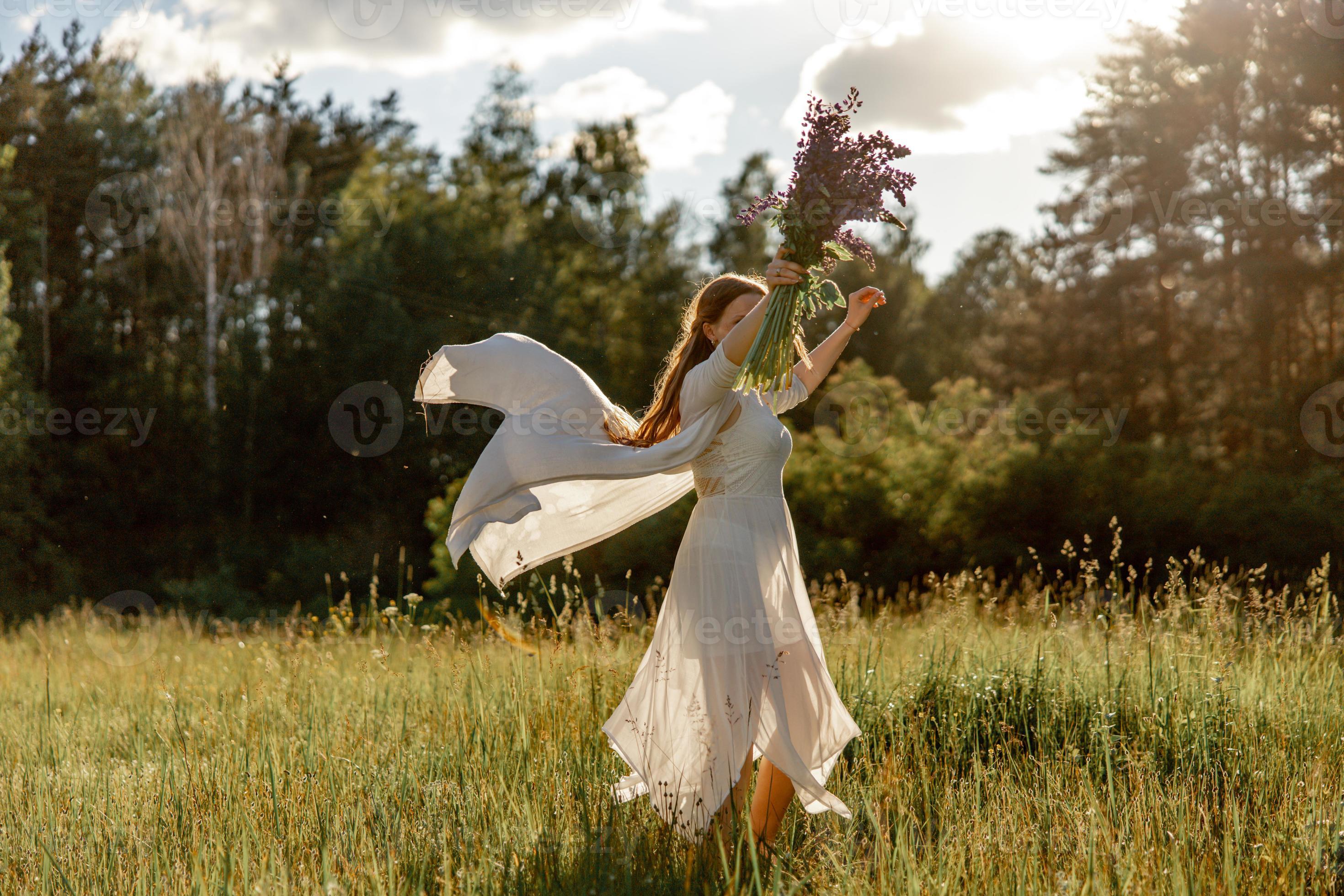 Young beautiful woman, wearing white dress, holding and dancing on the Girl joying nature and freedom. Natural beauty. Dance, Mental health, stress free, dreaming. Sunset. Stock Photo at