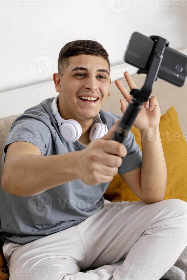 Young man, blogger recording lifestyle blog, talking to camera of smartphone on tripod. Young influencer filming vlog for his channel. Man makes video for his followers online. photo