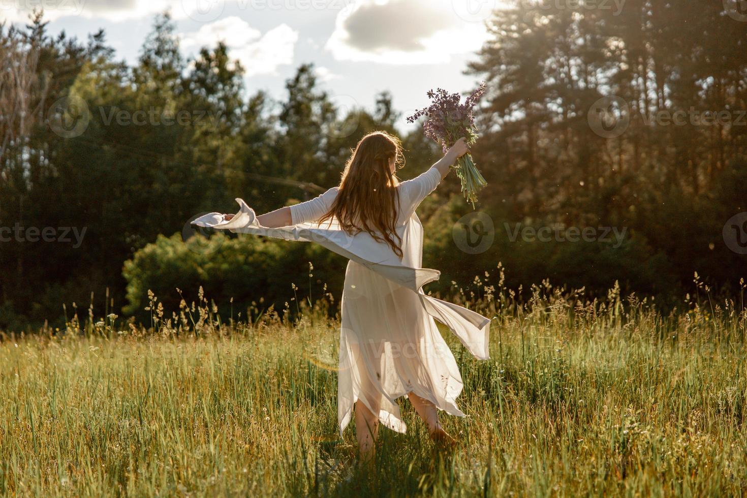 Young beautiful woman, wearing white dress, holding flowers and dancing