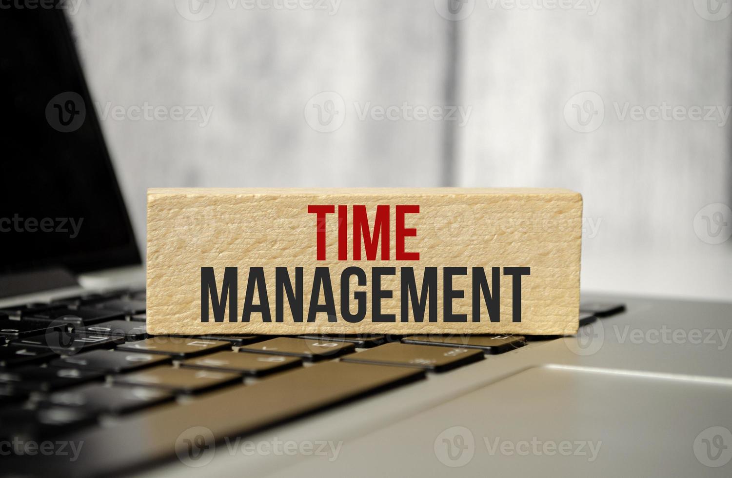 Word time management on wooden block with laptop on wooden background photo