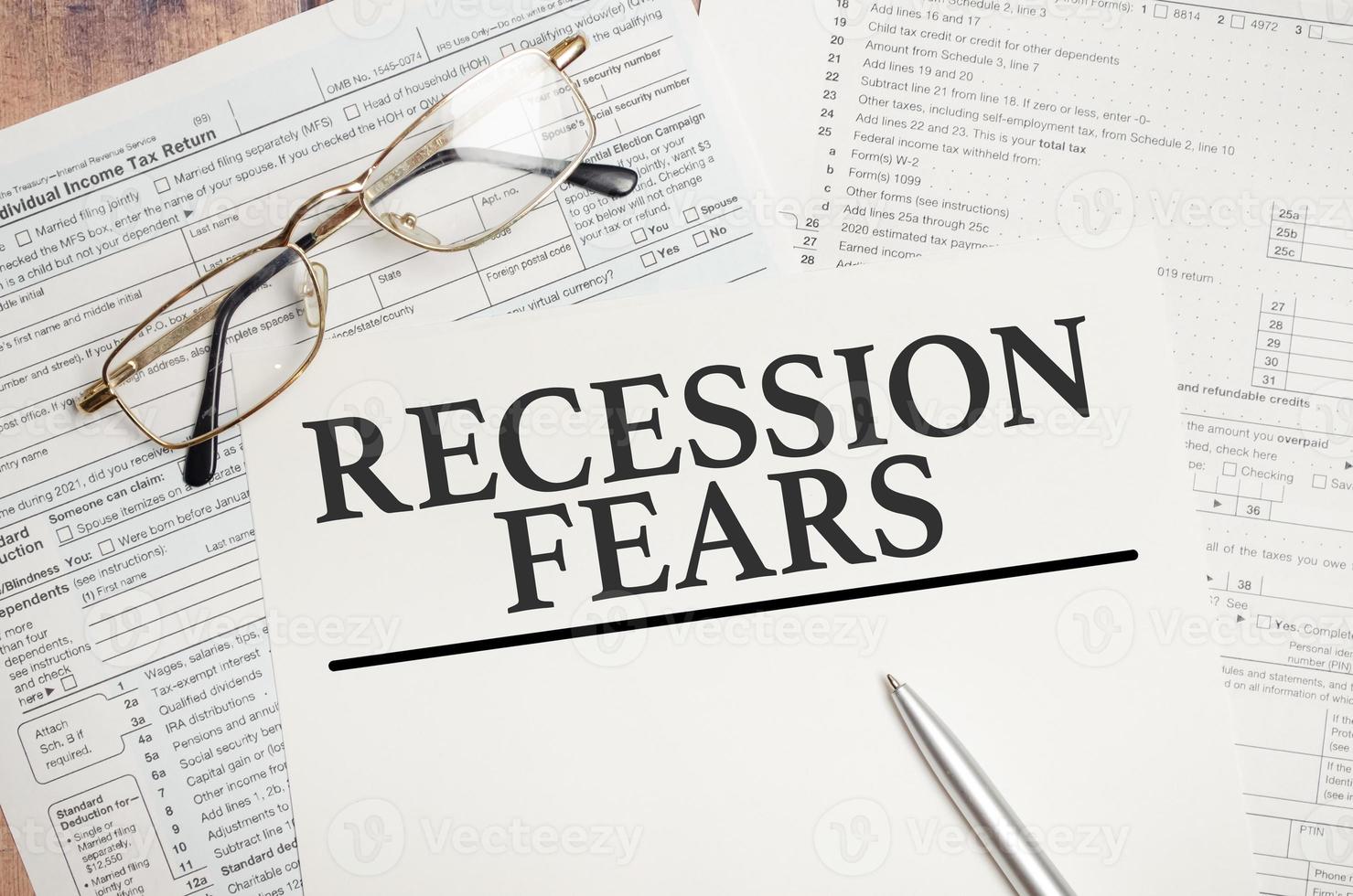 Recession fears symbol. Words on white paper with tax forms photo