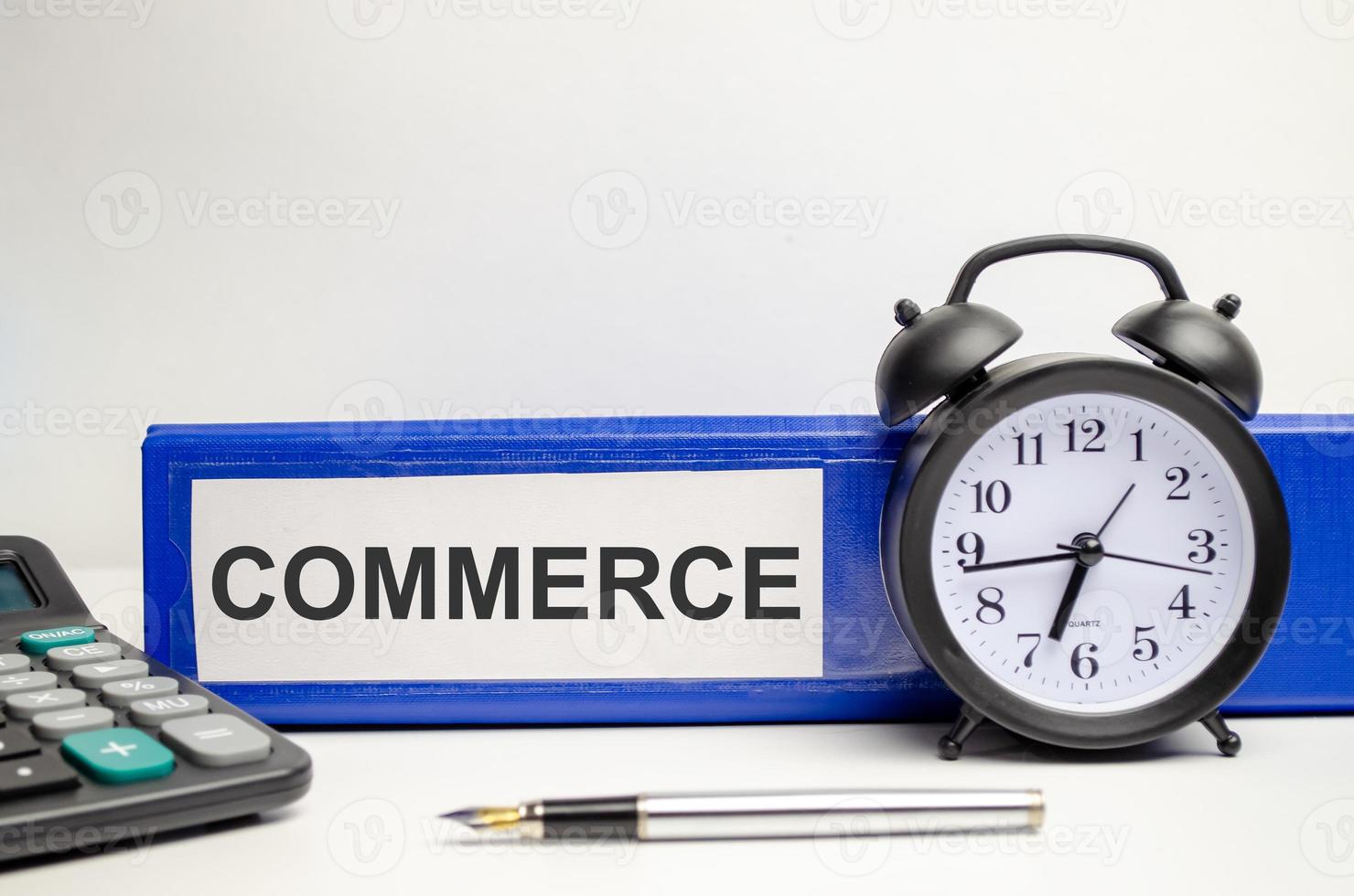 word commerce on blue paper folder and clock with calculator photo