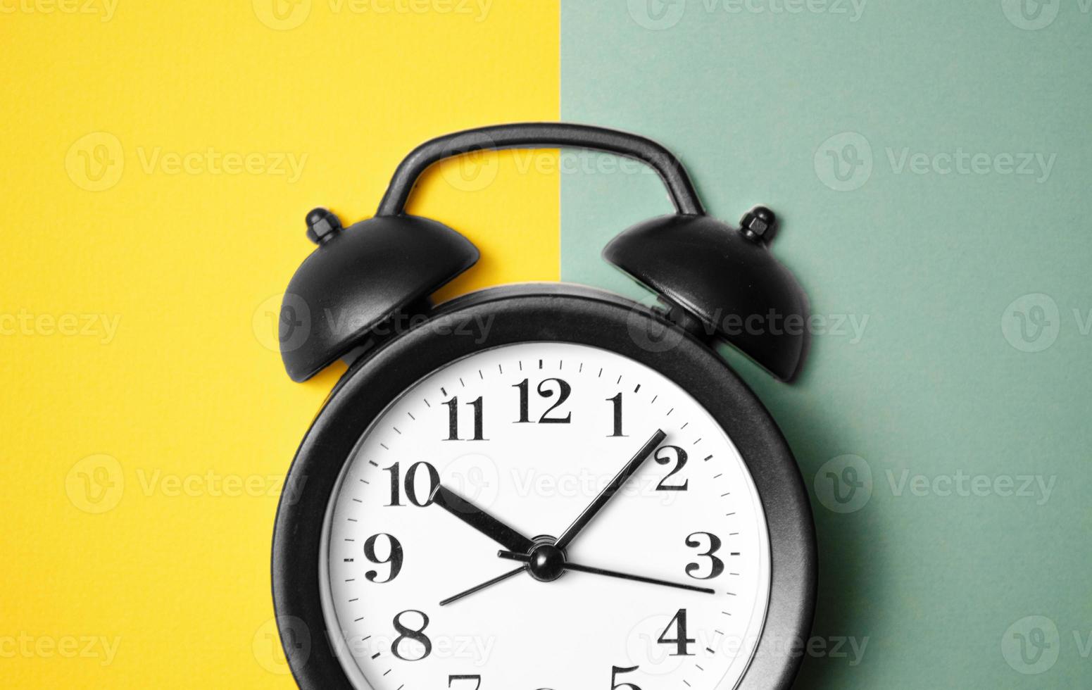 Ringing twin bell vintage classic alarm clock on yellow green pastel paper photo