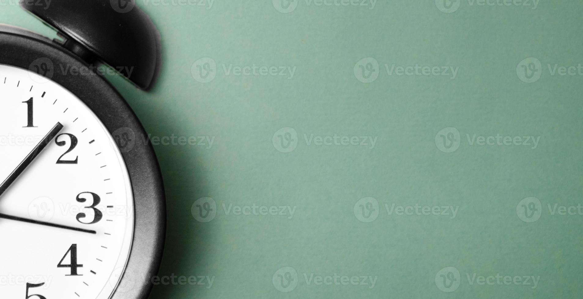 Ringing twin bell vintage classic alarm clock on green pastel paper photo