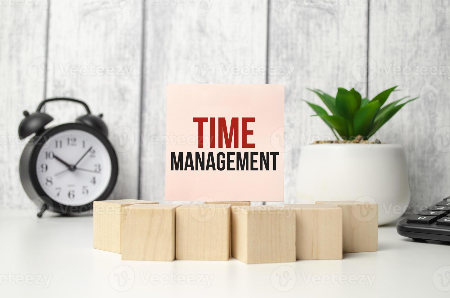 time management on pink sticker with wooden block and alarm clock photo