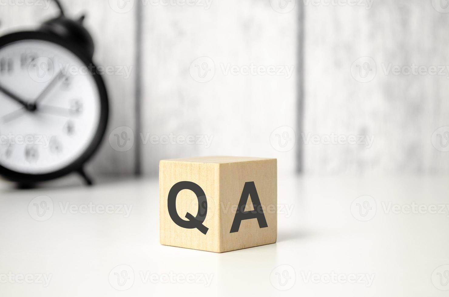 qa symbol word on wooden blocks and alarm clock photo