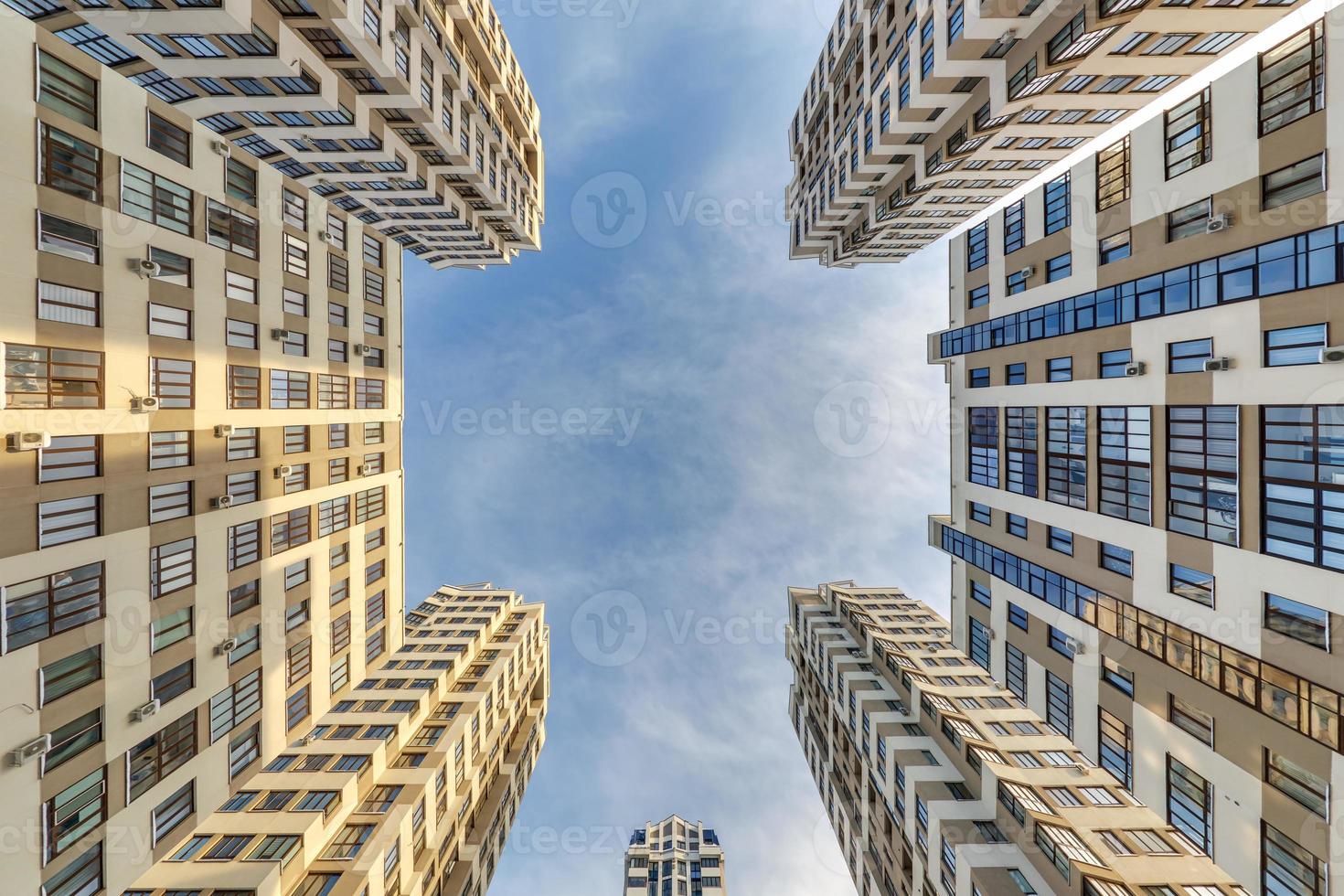 view up from ground to blue sky among skyscrapers, look at house from bottom up photo